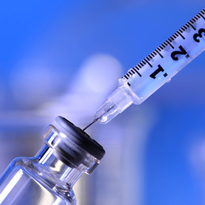 Syringe being inserted into a vial in a laboratory