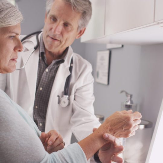 Senior male doctor assessing patient's fractured wrist